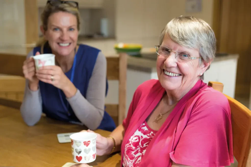 Elderly woman having a cup of tea with her care support worker