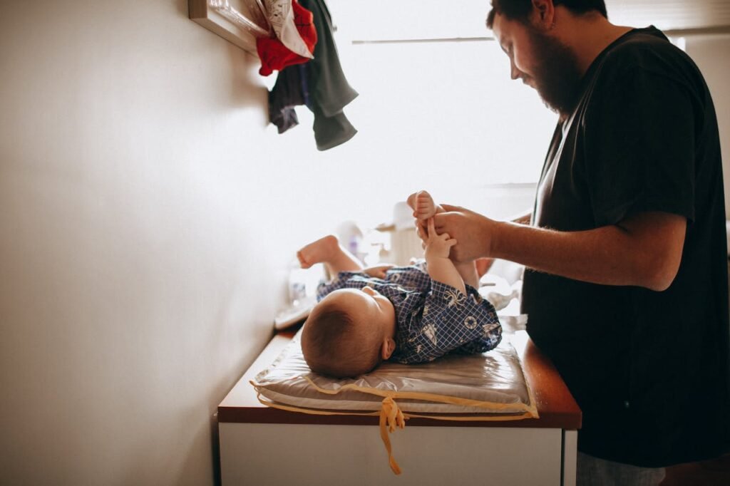 A loving father changes his baby's diaper in a warm, cozy home environment, emphasizing care and bonding.