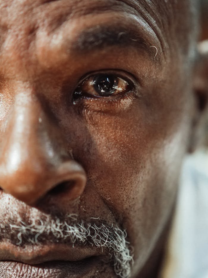 A close-up of an elderly man's face showing deep emotion and reflection.